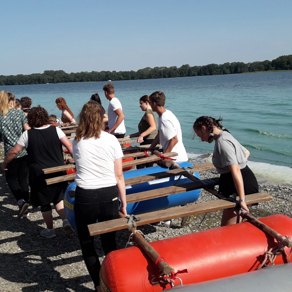 ein selbst gebautes Floss ins Wasser tragen